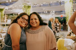 Guests sharing a warm embrace during a wedding reception under decorative lighting.
