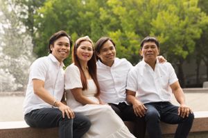 Group in matching white shirts sits casually together on outdoor bench.