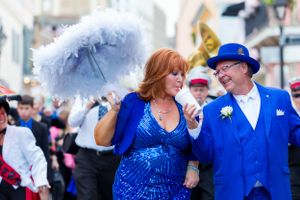 Energetic street performers with white parasols entertaining during a New Orleans style celebration.
