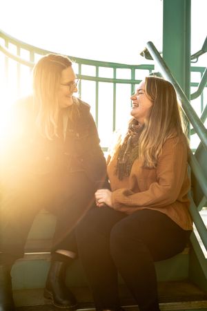 Two friends share a laugh while sitting in golden sunlight.