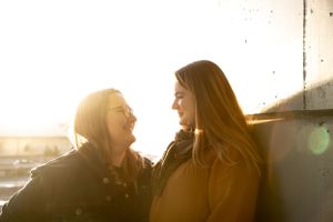 Two friends share a genuine laugh in warm sunset lighting.