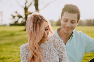 Close up of couple sharing tender moment in sunlit field with soft focus background.