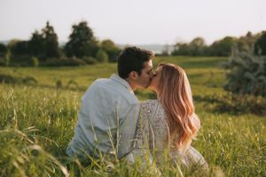A romantic moment shared between two people in a golden meadow at dusk.