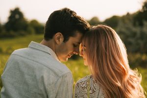 An intimate portrait of a couple sharing a close moment in a sunlit meadow.