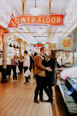 A couple dances in Pike Place Market under a Lower Floor sign.