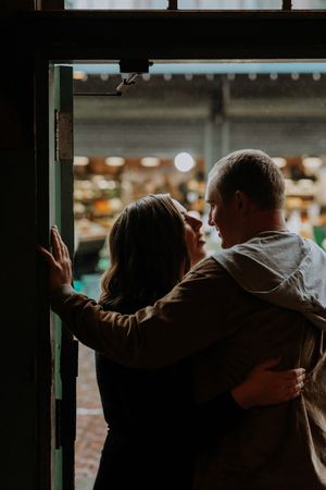 A romantic silhouette of a couple embracing in a doorway with bokeh lights in the background.