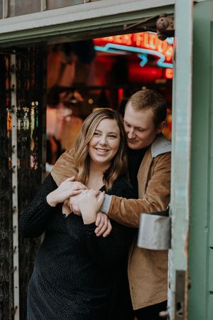A couple sharing a joyful moment outside a storefront with neon lights.