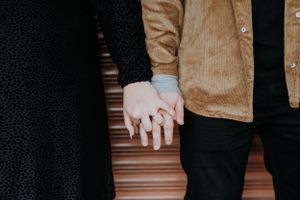 Close-up shot of two people holding hands against an industrial background.