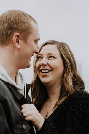 A couple laughs together in a candid black and white portrait.