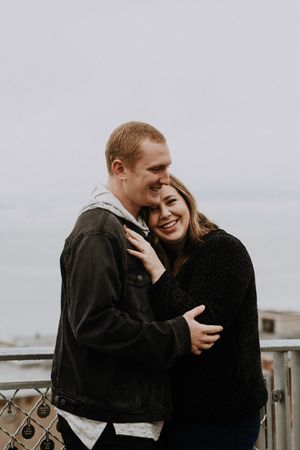 A romantic couple shares an intimate embrace on a foggy day outdoors.