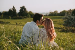 An intimate forehead touching moment between a couple in a sunlit field.