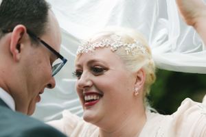A candid wedding moment captured under a white tent with joyful expressions.