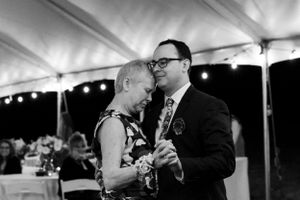 An intimate dance shared under a reception tent with twinkling lights overhead.