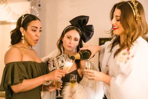 Three celebratory friends toasting with champagne glasses at an elegant indoor party.