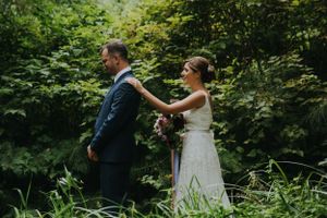A playful wedding moment captured in a green forest setting.