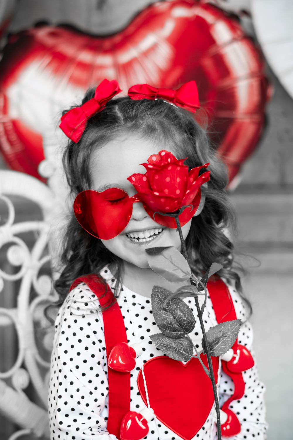Creative Valentine's themed photo with selective red coloring showing polka dot dress and heart balloons.