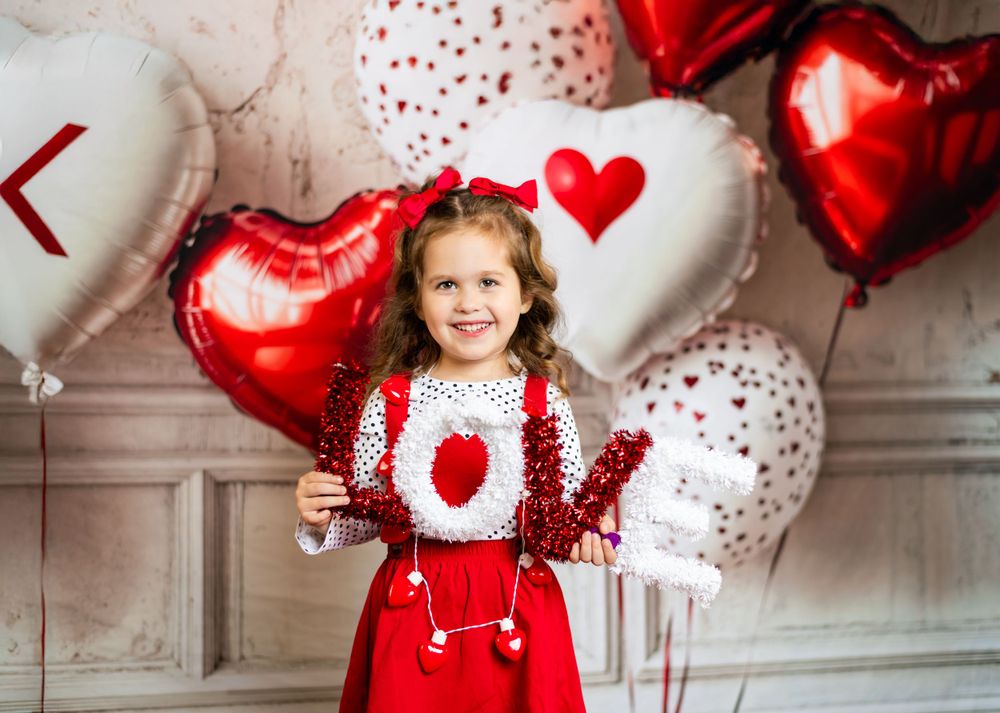 Red and white Valentine's Day themed photo setup with heart balloons and festive decor in studio setting.