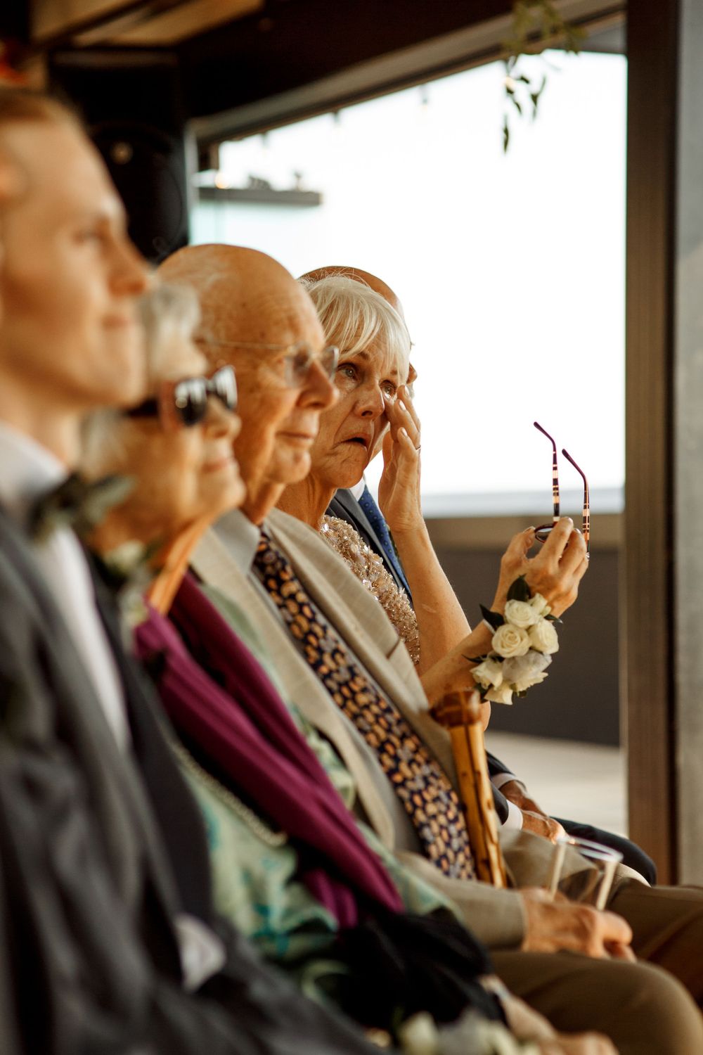 Guests watching emotional wedding ceremony while seated in elegant attire.