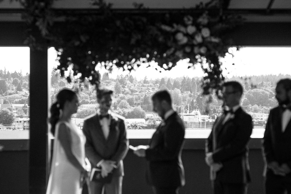 Wedding ceremony silhouette in front of large windows with city views.