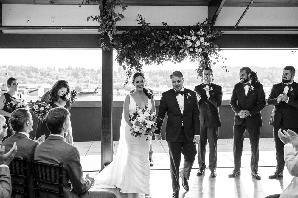 Black and white photo of wedding celebration with guests seated in elegant indoor venue.