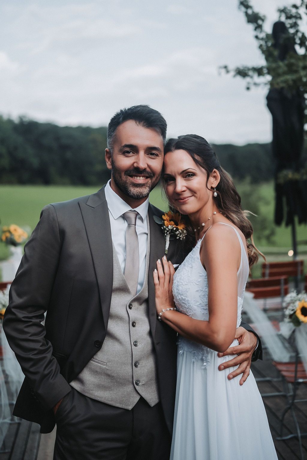 A happy couple shares romantic moments in formal attire during their outdoor wedding celebration.