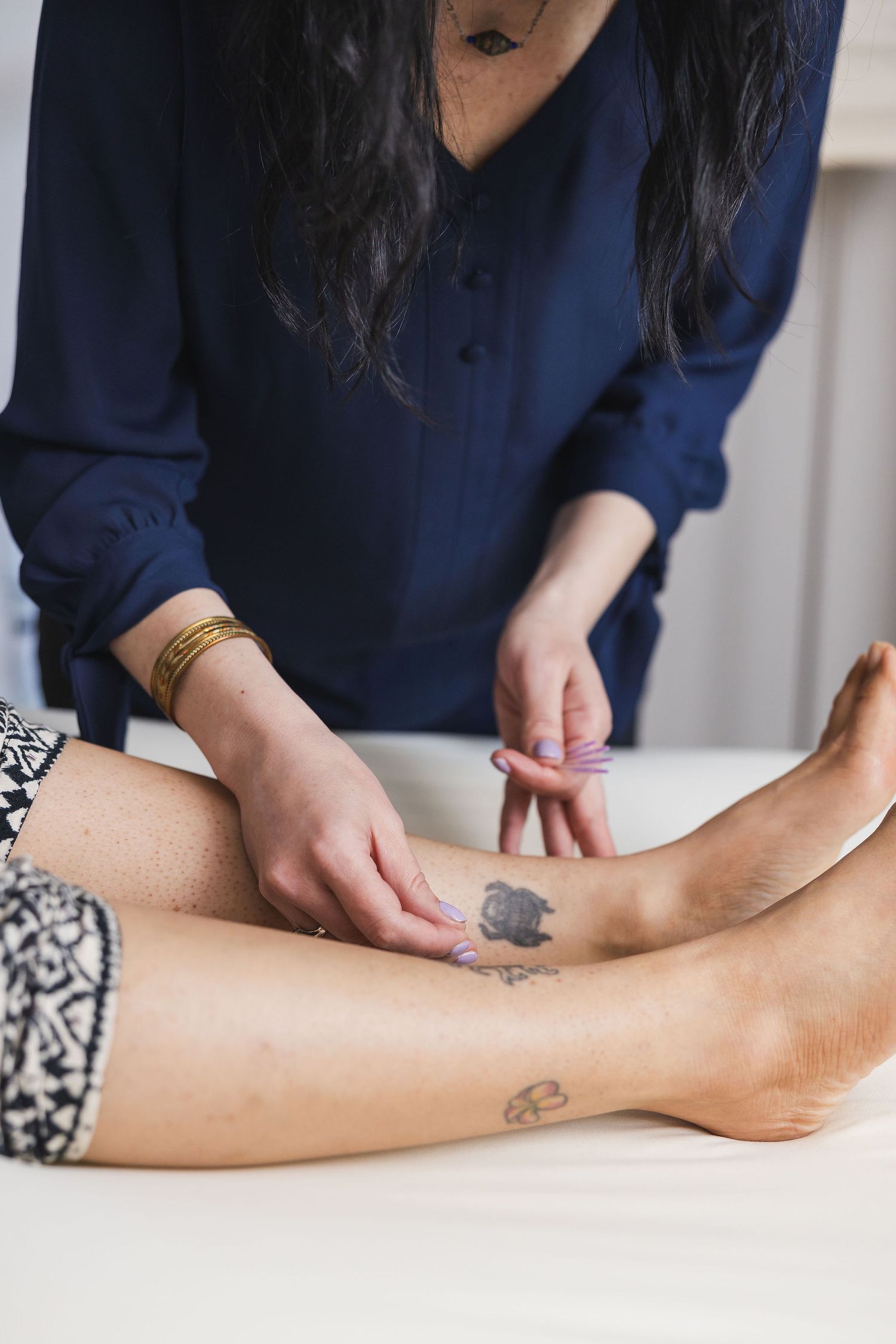 Maple Valley Acupuncture, WA branding photo of female acupuncturist inserting needles on inner lower leg near woman's ankles