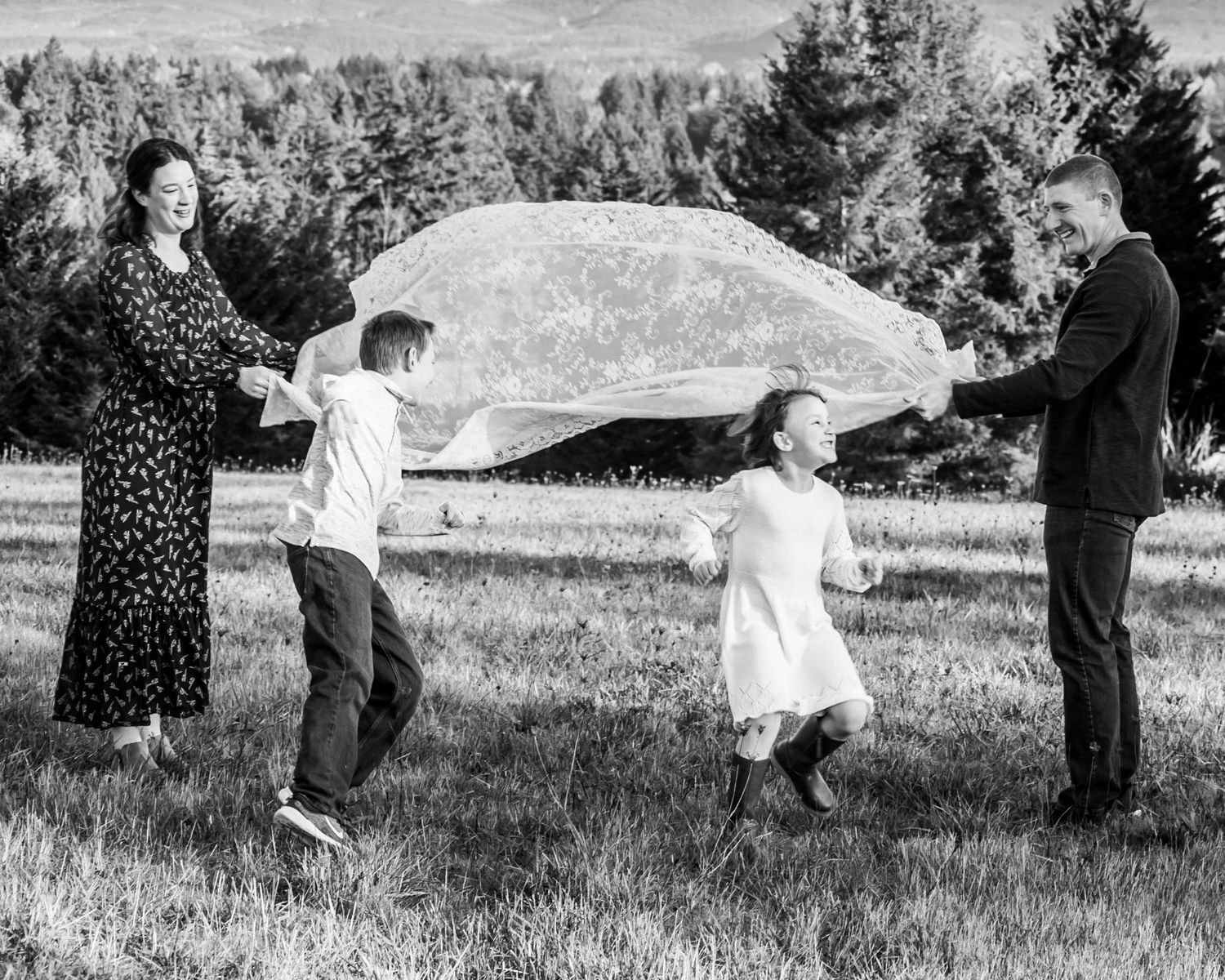 Family members play together in a grassy field during a sunny outdoor photo session.