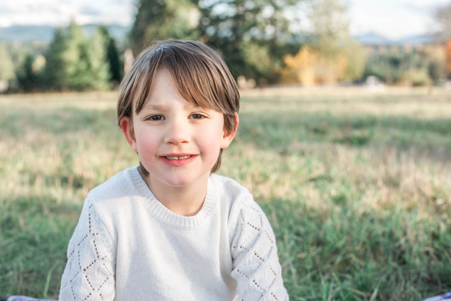 Children pose for casual portraits in a natural outdoor setting with trees and grass.