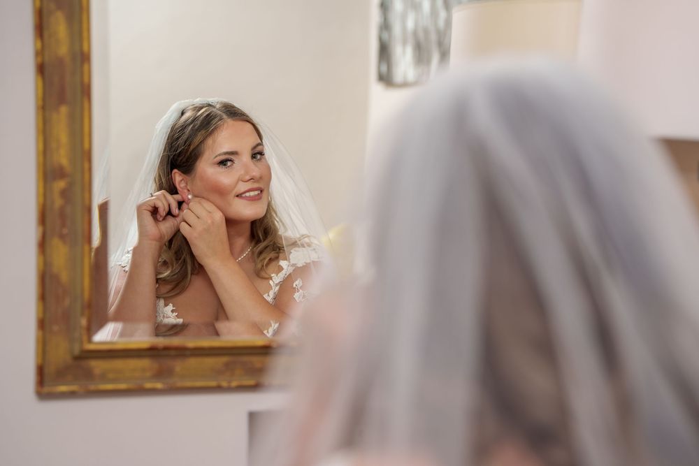 Elegant bridal preparation scene with rustic wooden mirror frame.