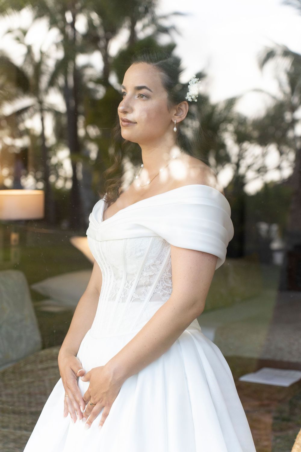 A classic white wedding gown photographed outdoors at sunset with palm trees in the background.