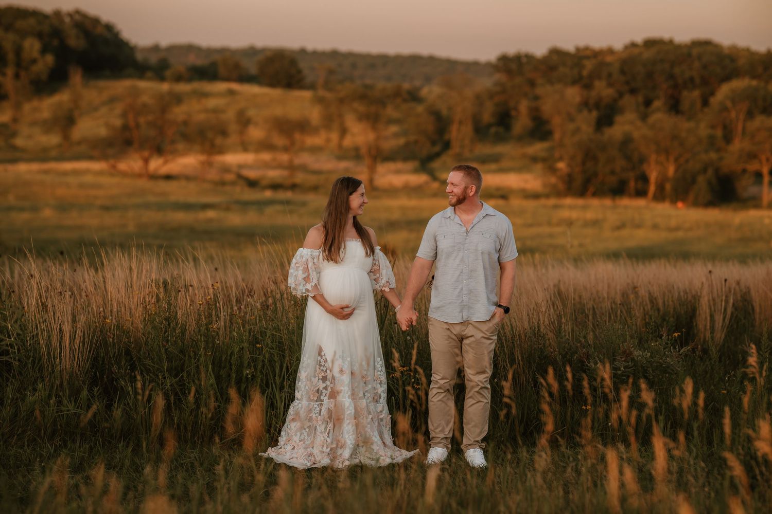 Couple shares romantic moments in golden field at sunset during outdoor engagement photo session.