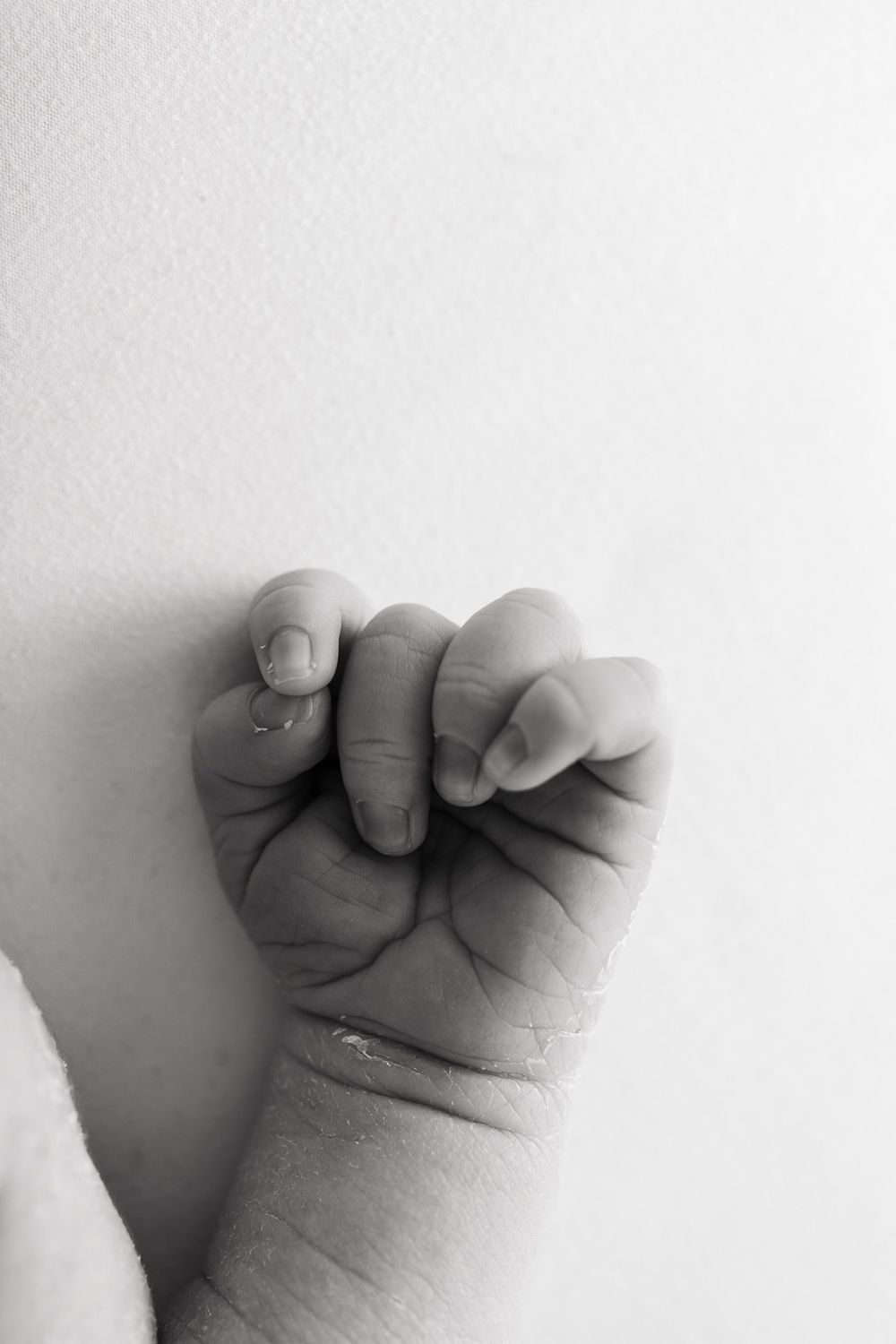 A sequence of black and white photographs showing a baby's tiny clenched fist from different angles.