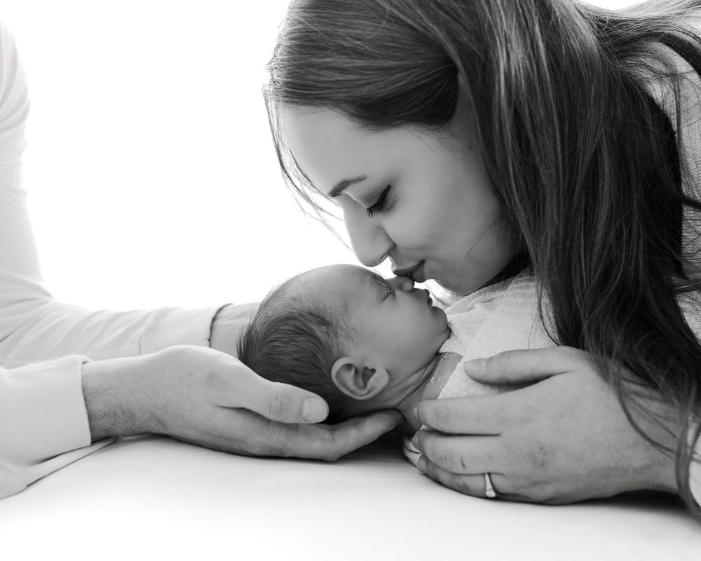 Monochrome series capturing intimate bonding moments between caregiver and infant in minimalist setting.