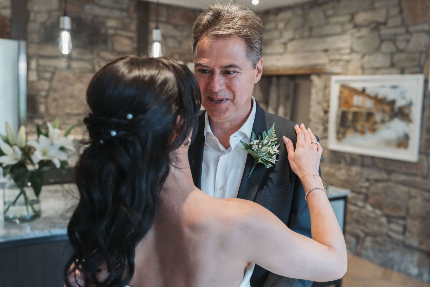 Wedding couple shares intimate moments during their first dance at a rustic stone-walled venue.