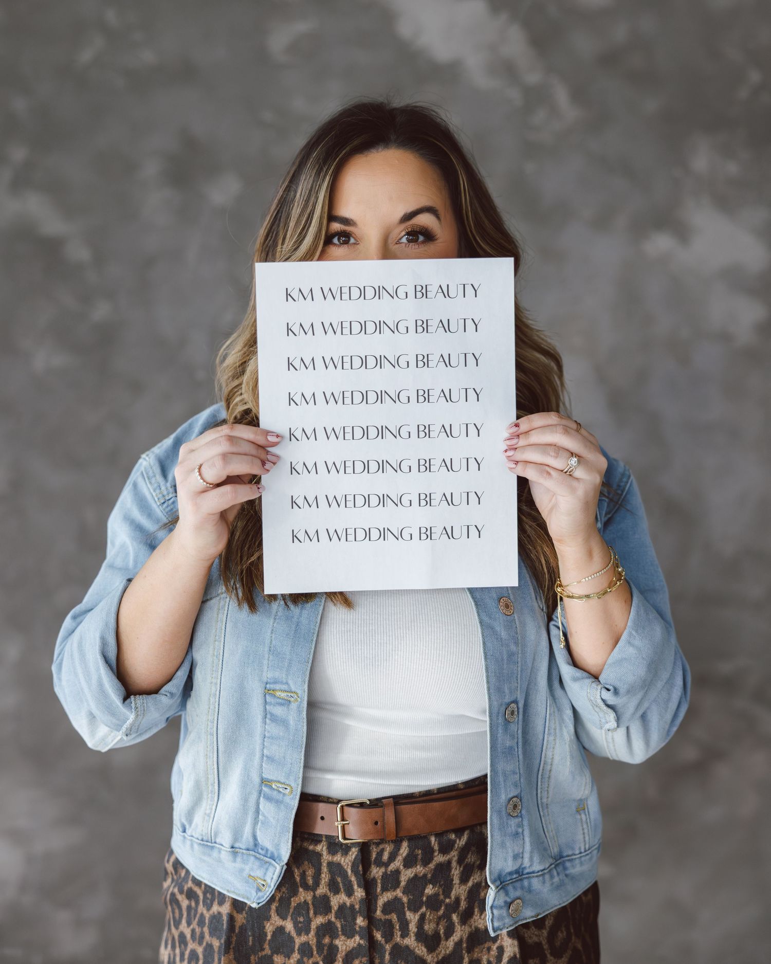 Fashion blogger in denim jacket and leopard skirt holds text cards against gray background in progressive photo series.
