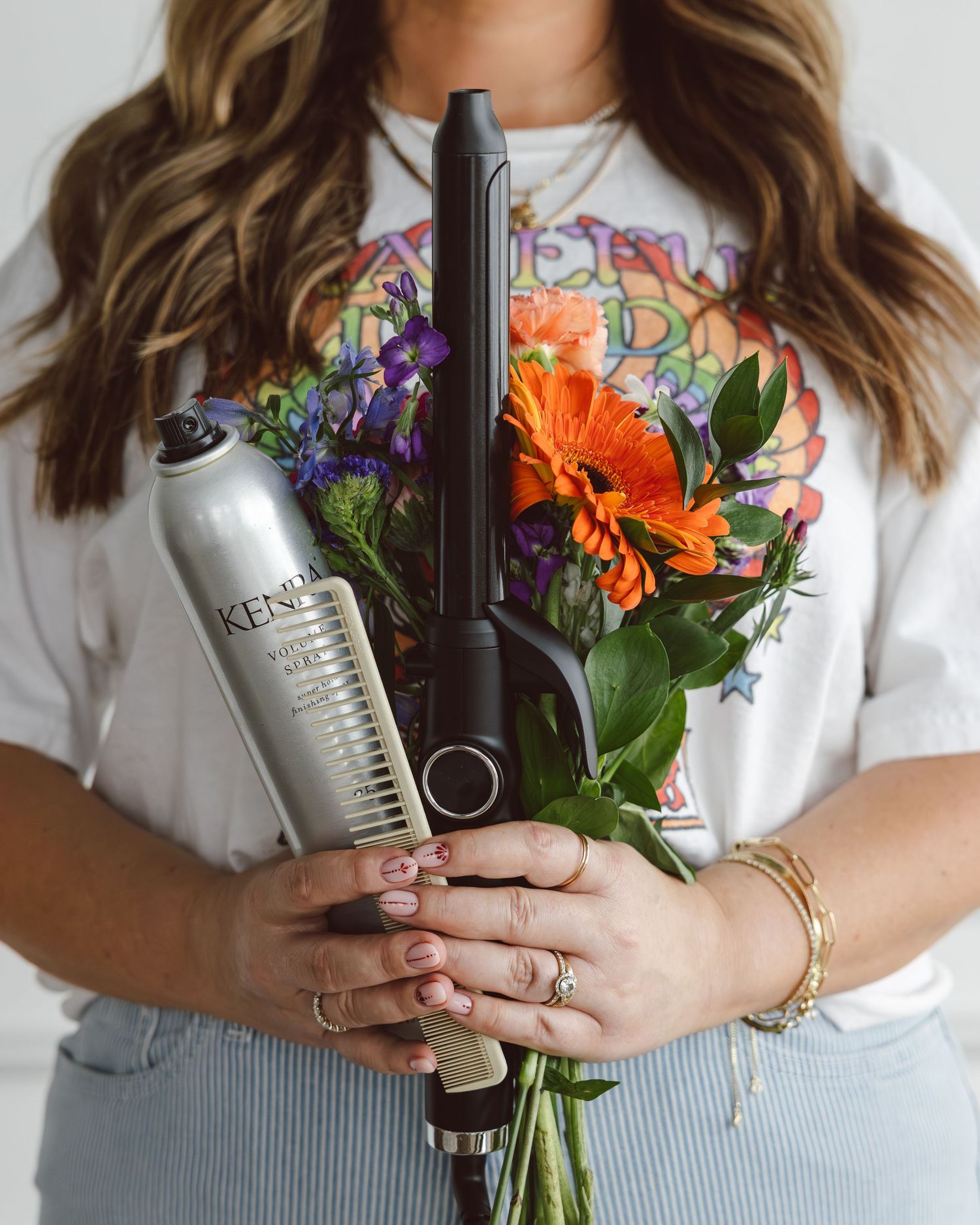 Hands holding wine bottles and colorful flowers against white background in lifestyle product photography.