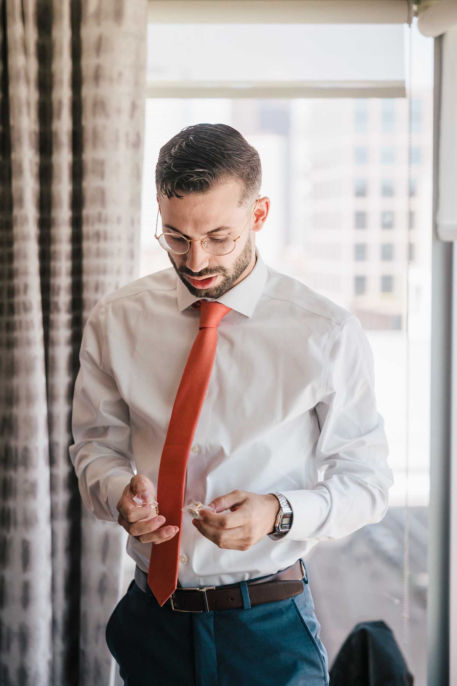 Groom putting on cufflinks while getting ready for a Boston wedding