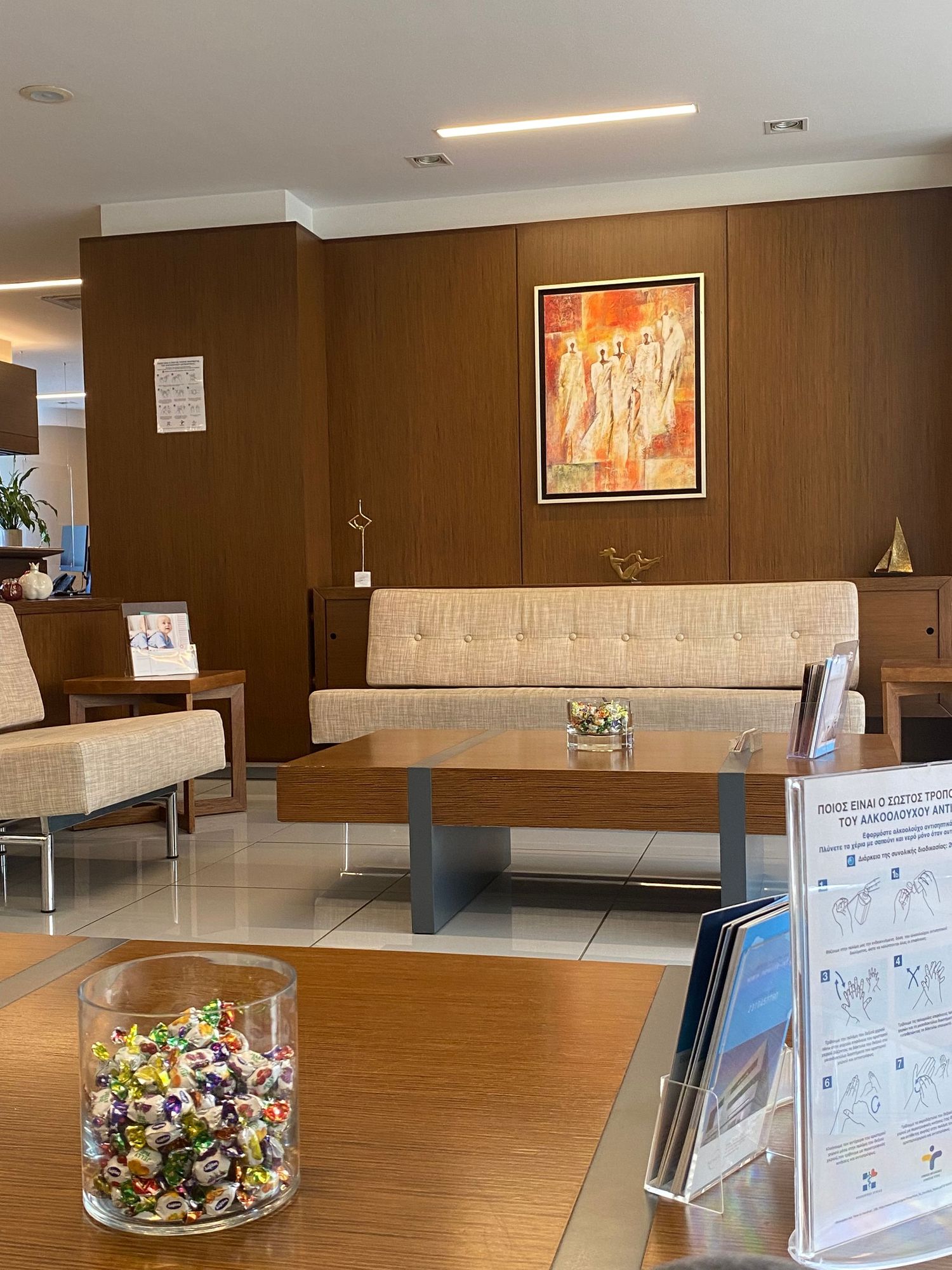 Modern office lobby with brown walls features sleek benches, wall art, and a decorative glass bowl filled with colorful ornaments.