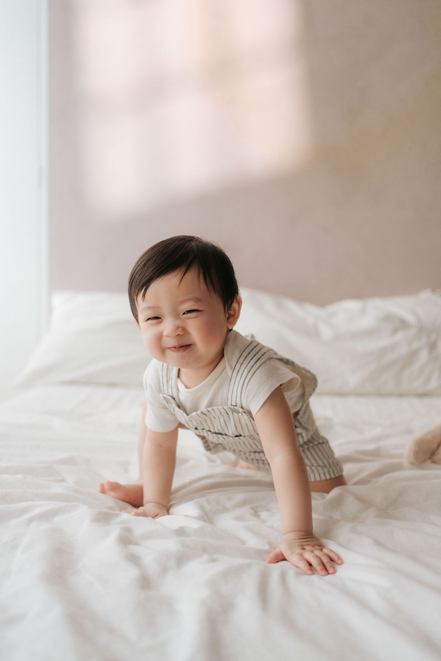 A tender moment between parent and child in soft white tones as they share cuddles and laughter on a couch.在柔和的白色調中，父母和孩子在沙發上擁抱、歡笑，溫馨的一刻。