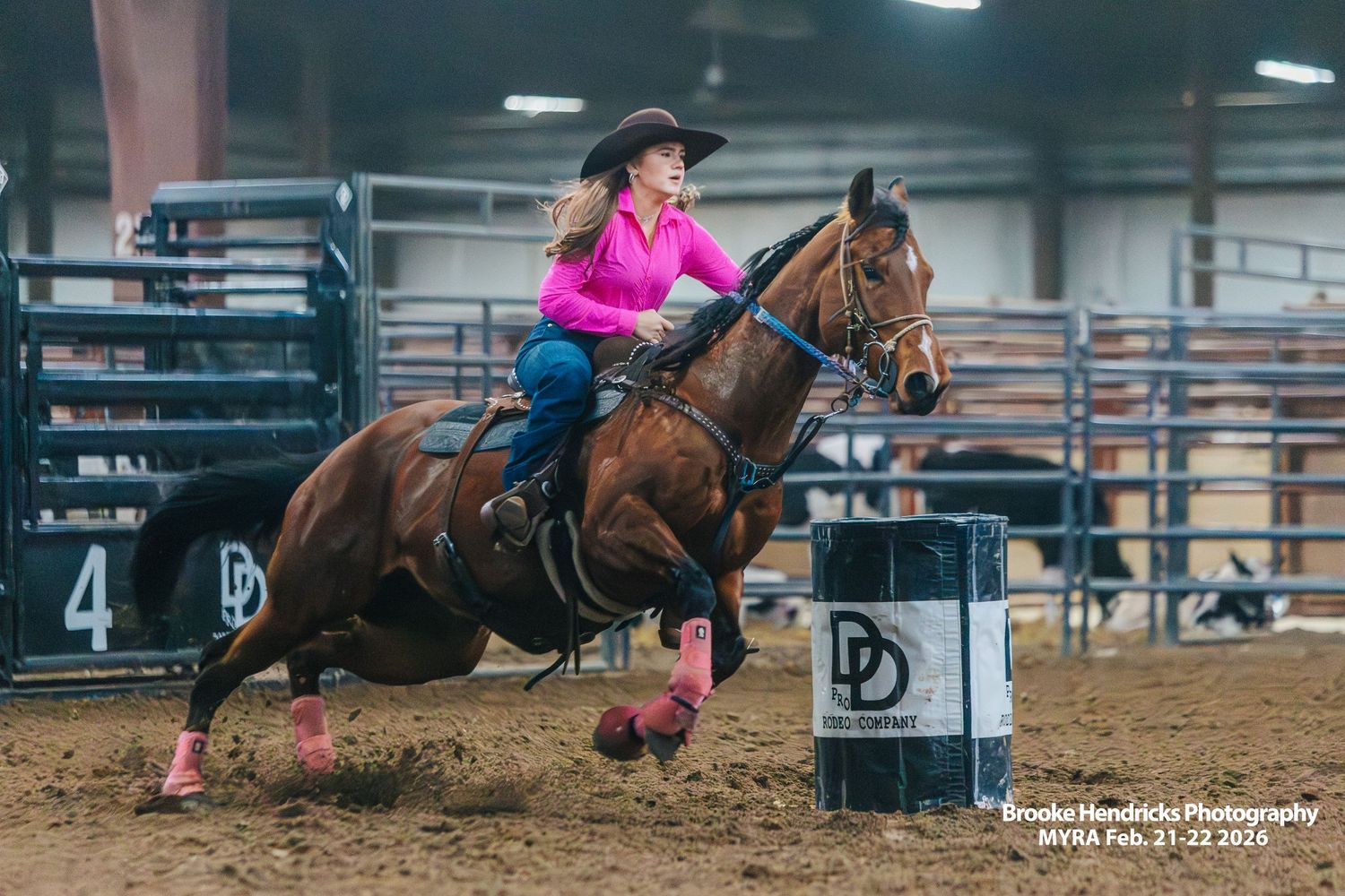 Barrel racing competition sequence showing horse and rider making tight turns around barrels in indoor arena.