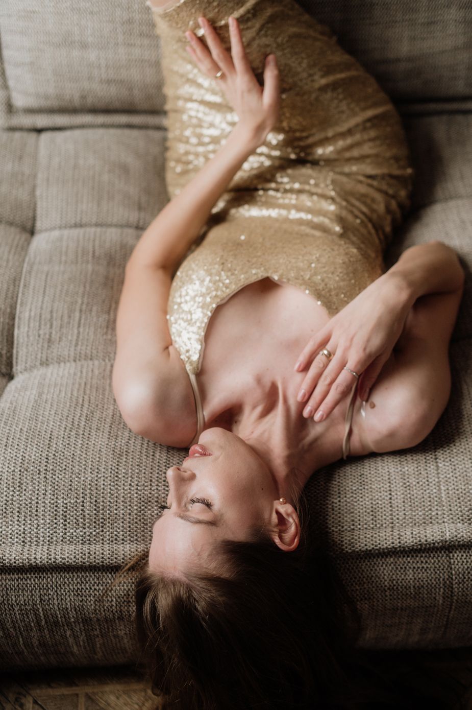 A series of artistic boudoir photos showing a person in a gold sequin dress reclining on a gray couch.