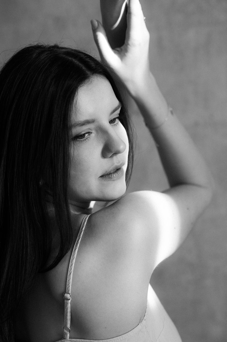 Artistic black and white portrait series showing a person's shoulder and neck in dramatic lighting.