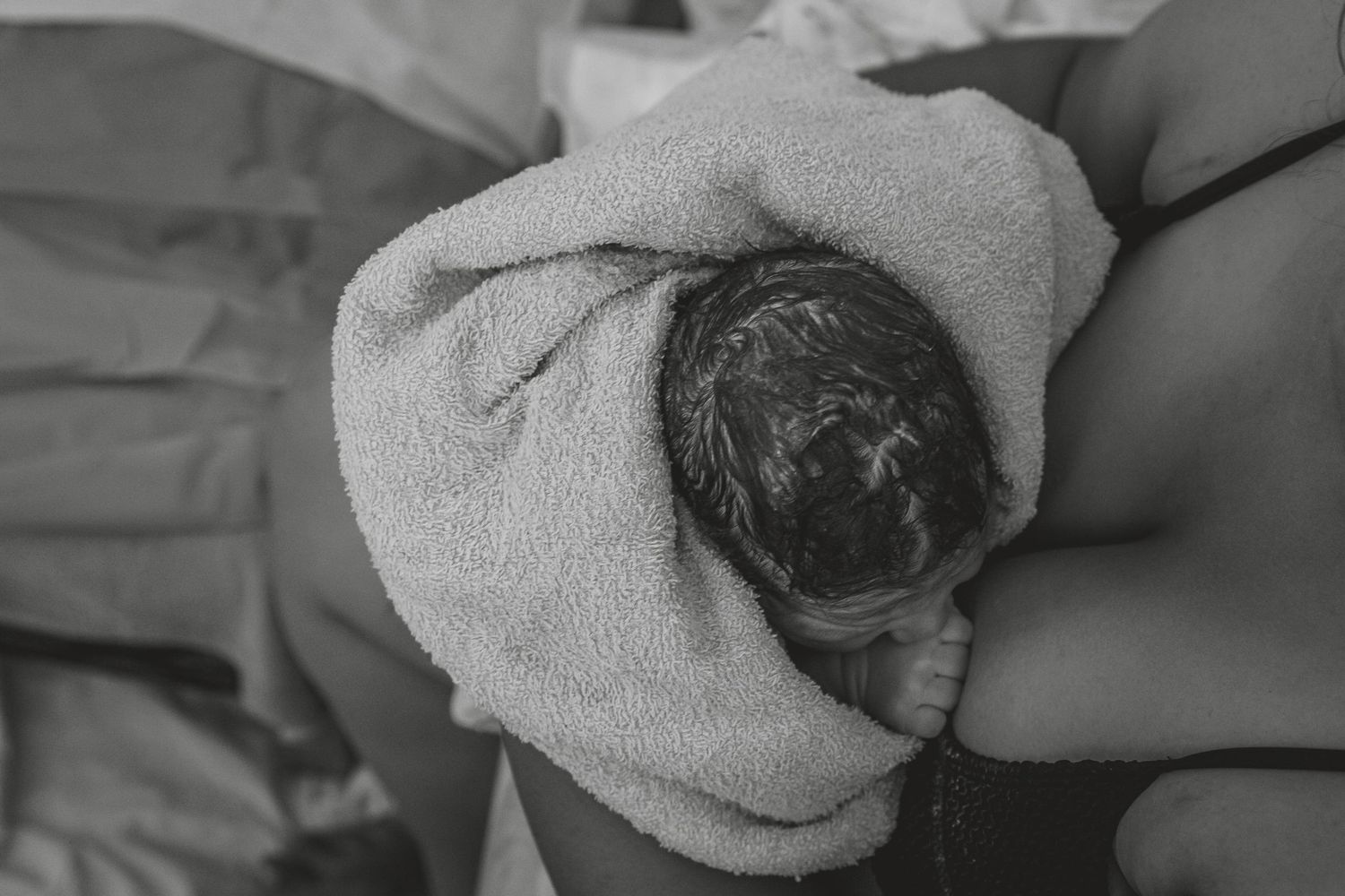 A sequence of black and white photos showing a newborn baby being wrapped in a white towel after bathing.