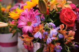 Colorful bouquet featuring pink daisies, roses, orange alstroemeria, and purple wildflowers in full bloom.