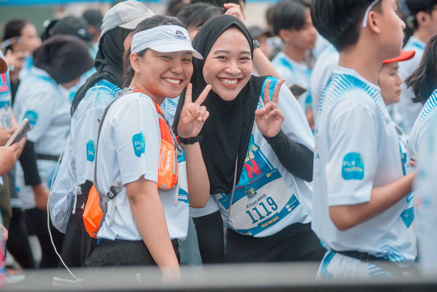 Crowd of spectators watching and taking photos at an outdoor event with a blue-tinted atmosphere.