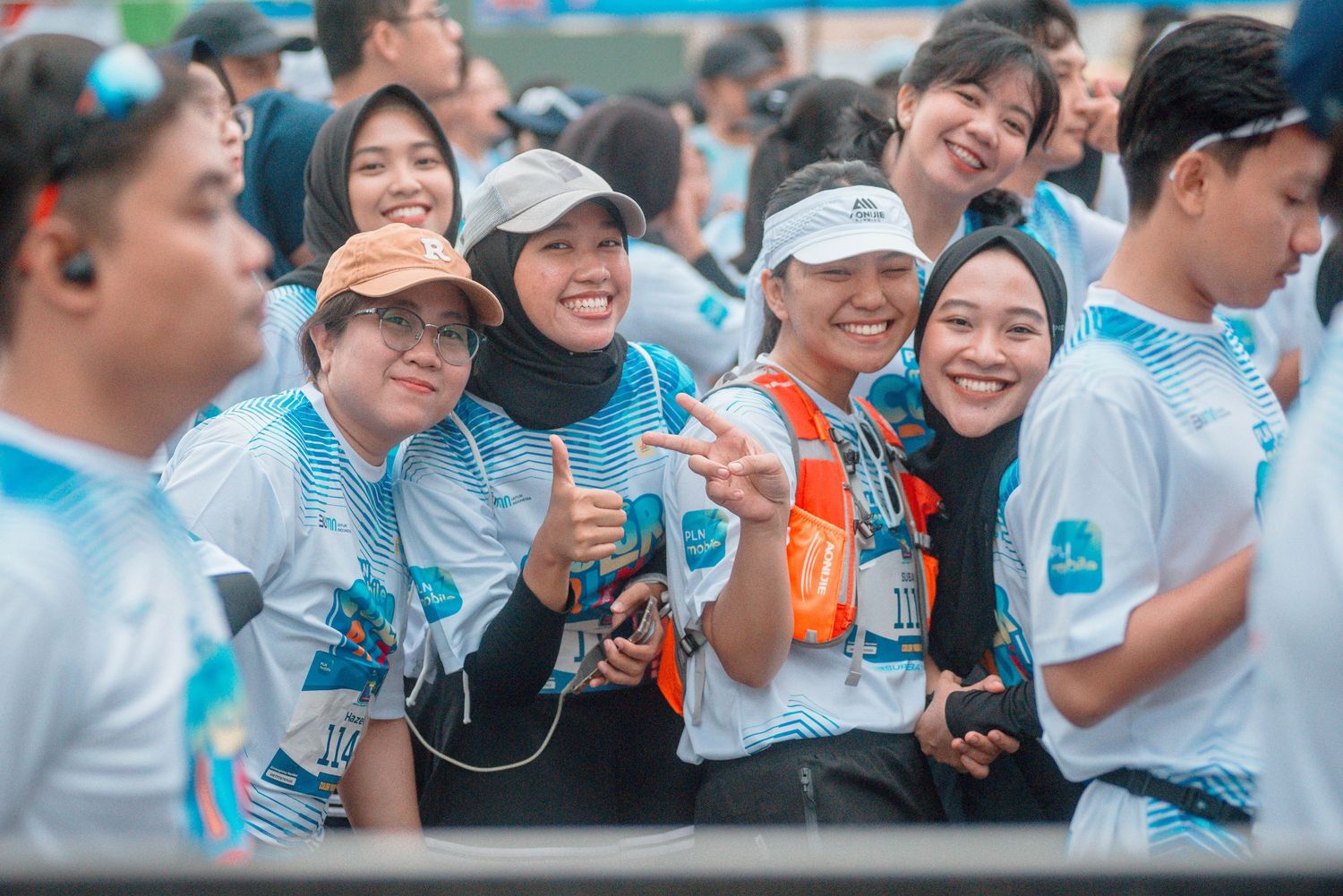 A cheerful group wearing white t-shirts and holding water bottles at an outdoor event with blue accents.