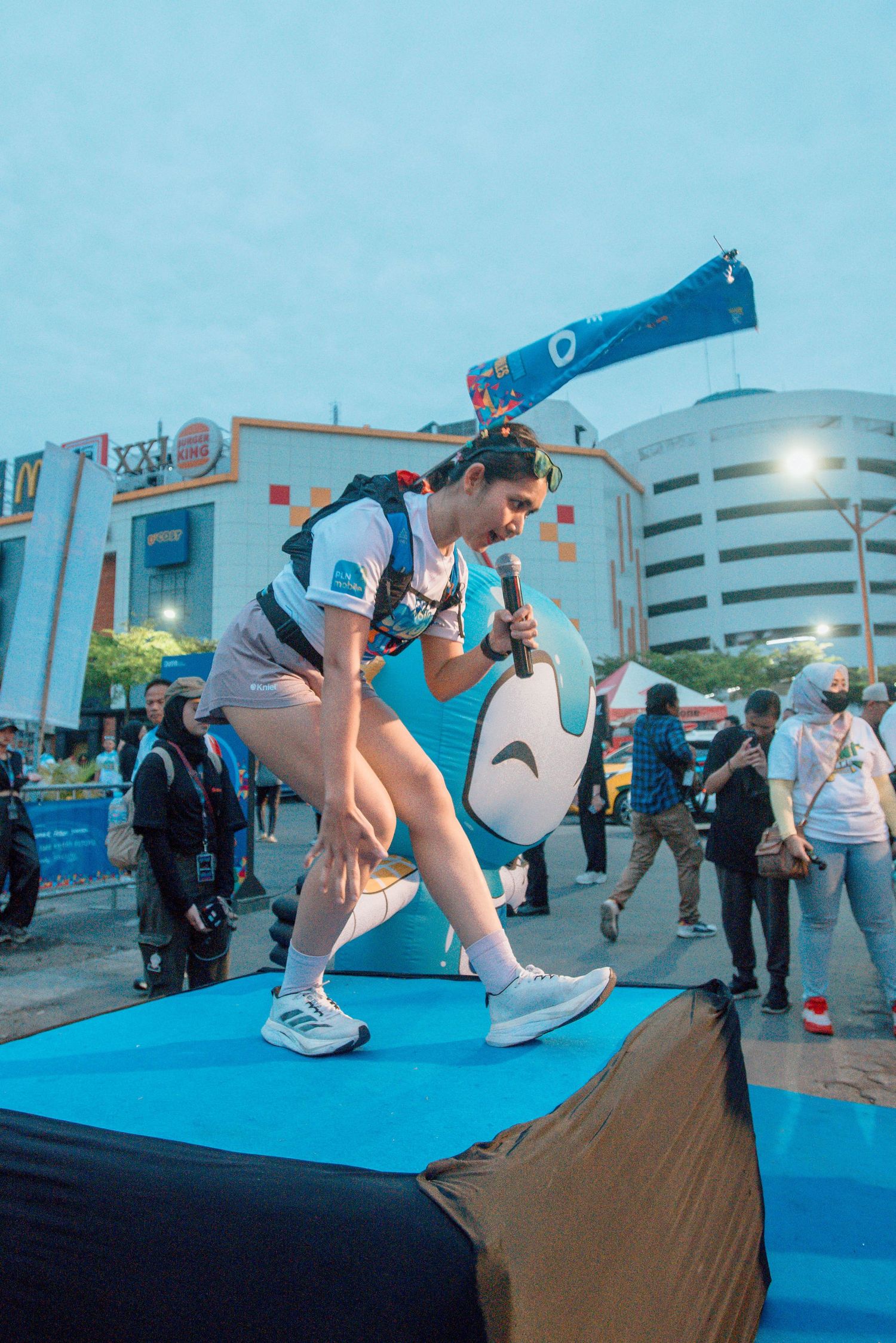 Sequence of action shots showing a person performing a breakdance move on a blue mat at an outdoor event.