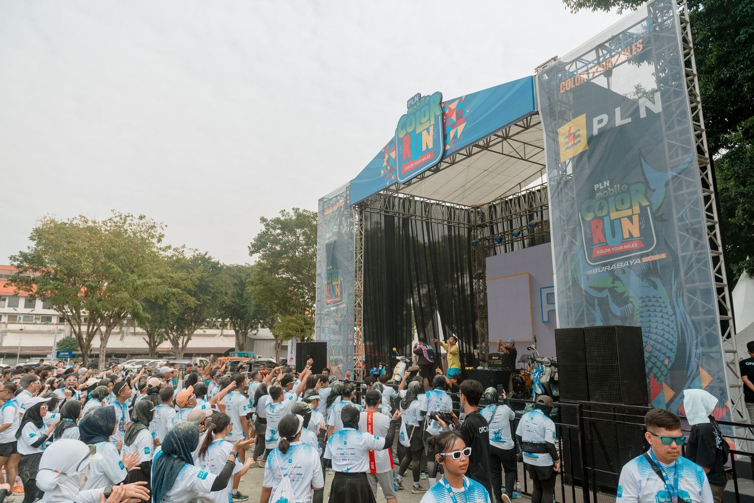 Large crowd in light blue shirts gathered at an outdoor concert stage with University of Miami branding.