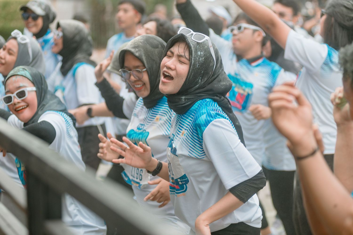 Crowd of enthusiastic participants in matching blue and white uniforms cheering at an outdoor event.