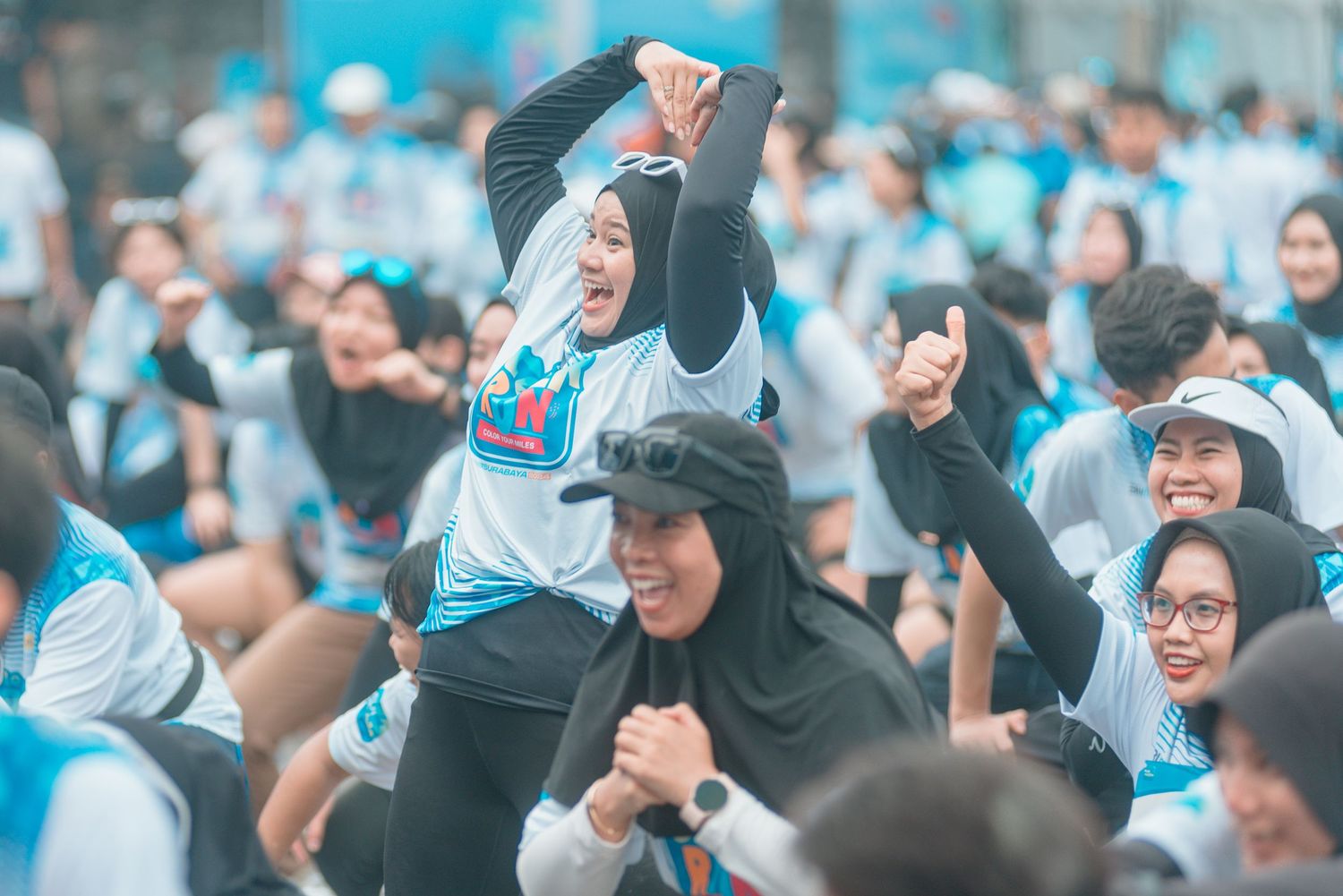 A large crowd of excited fans in light blue shirts cheer and celebrate during a sporting event.